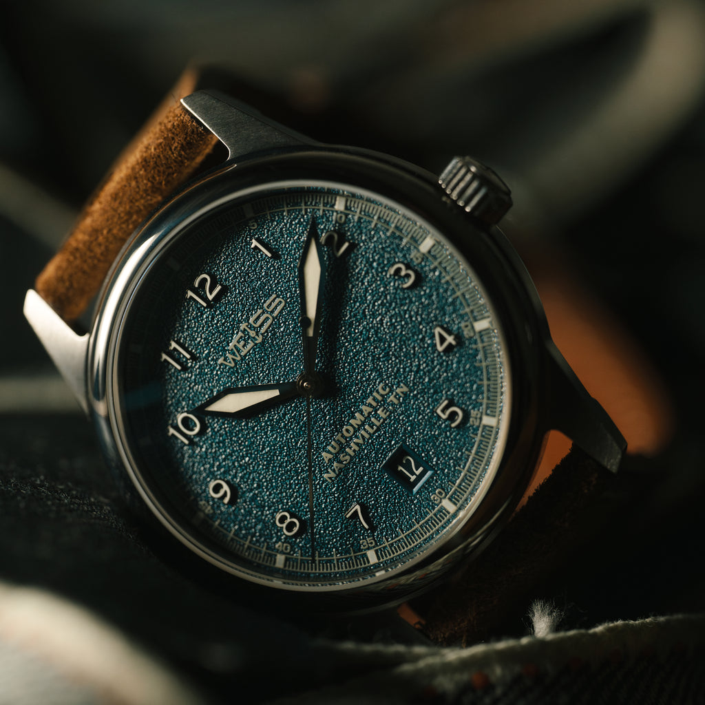 Watch with a blue textured face and brown suede strap 